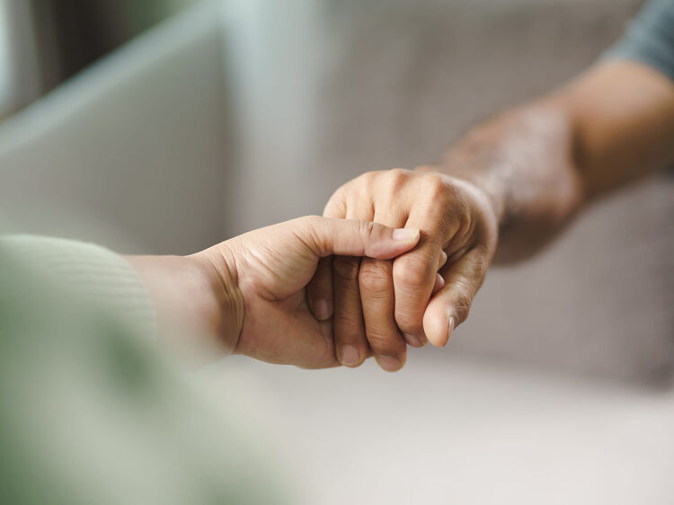 Two people clasping hands in a supportive gesture